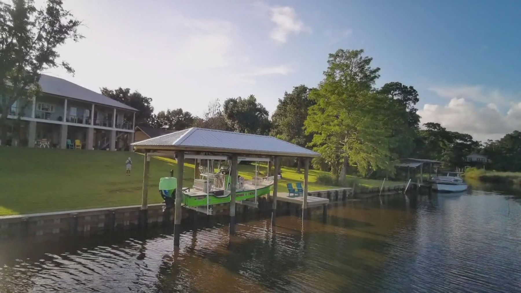Covered boathouse with boat lift and dock on a bulkheaded bayou lot