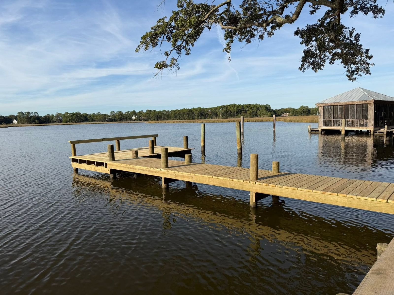 New wooden dock with a bench rail and pilings on the bayou